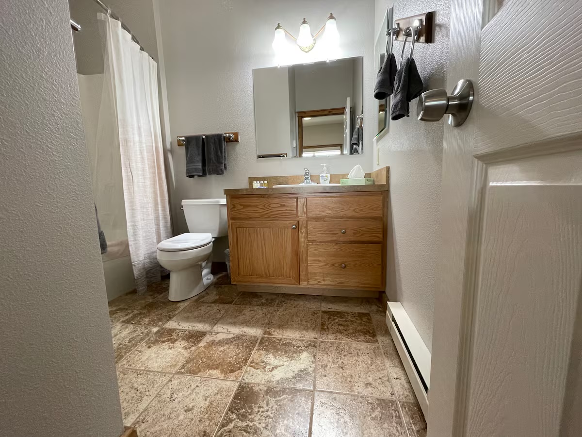 Bathroom with an oak vanity, a tub and shower and a tiled floor