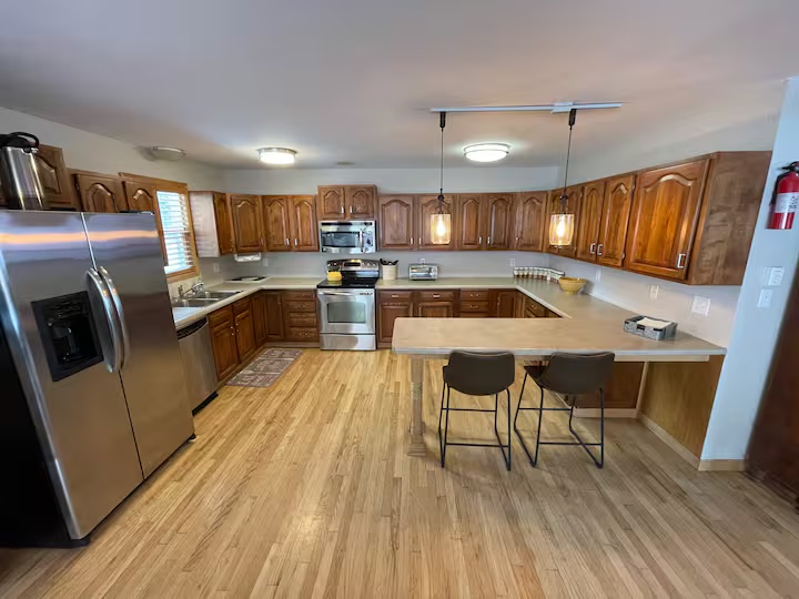 Kitchen with a stainless steel refrigerator and range, oak cabinets and a breakfast bar with stools