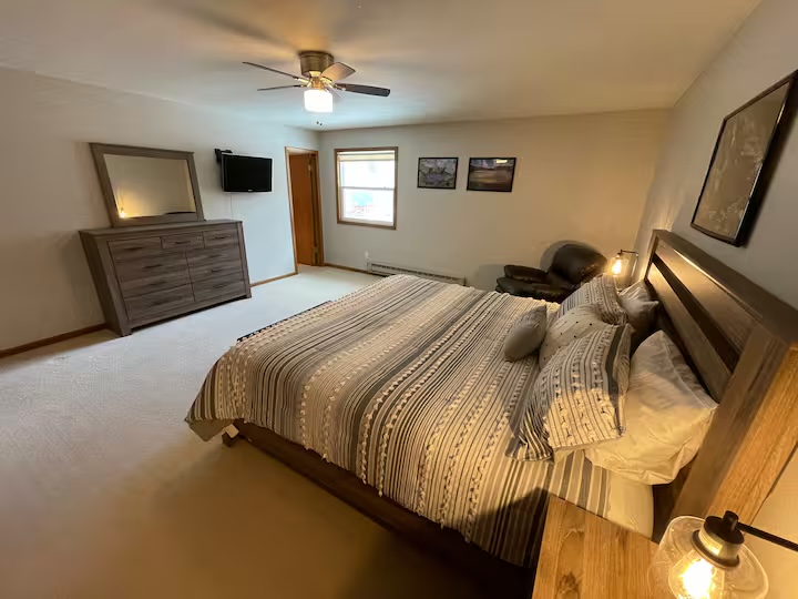 Bedroom with a dresser and mirror, a wall-mounted television and framed prints